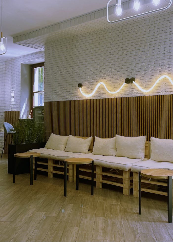 A stylish and cozy cafe interior featuring modern seating with soft cushions, wooden decor, and ambient lighting.